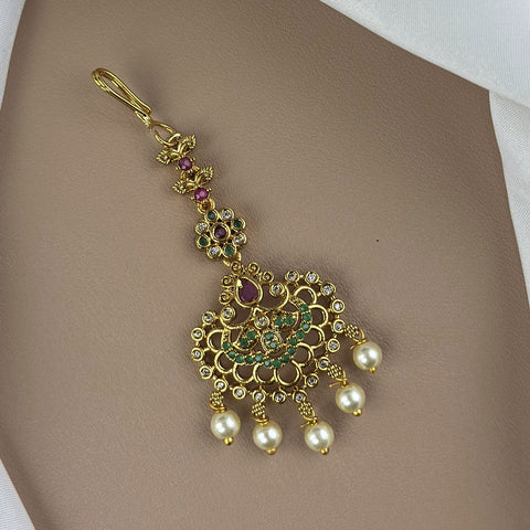 Decorative gold pendant with pearls and gemstones on a beige background