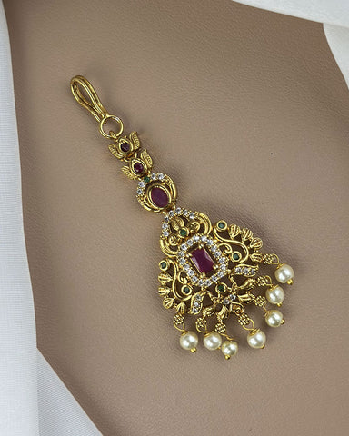 Gold pendant with red gemstones and pearls on a beige background