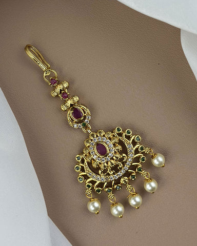 Gold pendant with pearls and gemstones on a neutral background