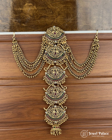Ornate gold necklace on a wooden surface with 'Jewel Palace' branding.