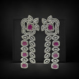 Pair of ornate earrings with pink gemstones on a black background