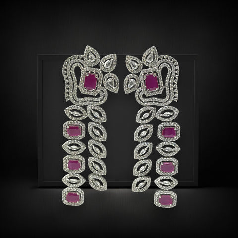 Pair of ornate earrings with pink gemstones on a black background