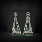 Pair of ornate earrings with green gemstones on a black background