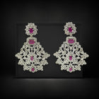 Pair of ornate earrings with pink gemstones on a black background