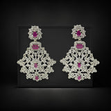 Pair of ornate earrings with pink gemstones on a black background