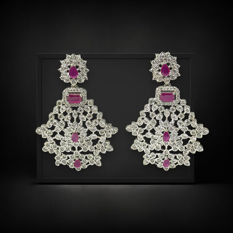 Pair of ornate earrings with pink gemstones on a black background