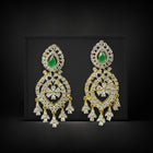 Ornate earrings with green gemstones on a black background