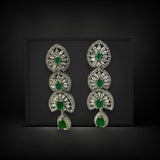 Pair of silver earrings with green gemstones on a black background