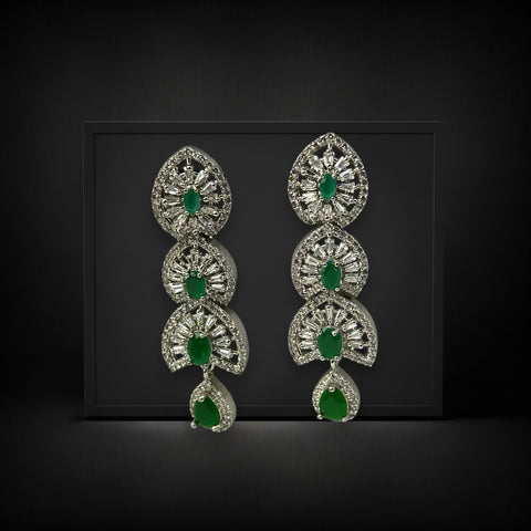 Pair of silver earrings with green gemstones on a black background