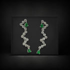 Pair of earrings with green gemstones and clear stones on a black background