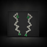 Pair of earrings with green gemstones and clear stones on a black background