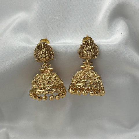 Gold earrings on a white satin background