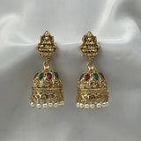 Gold earrings with intricate designs and pearl accents on a white satin background
