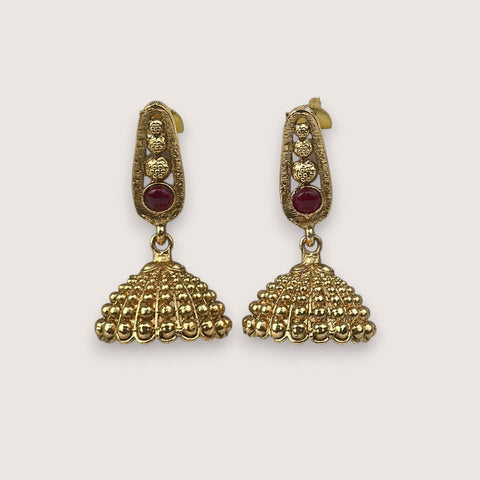 Pair of gold earrings with red gemstones on a light gray background