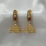 Gold earrings with red gemstones on a white satin background