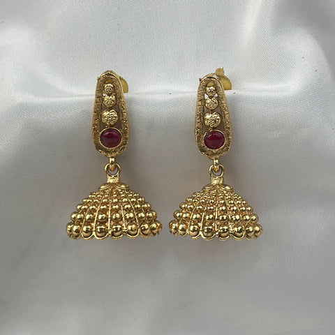 Gold earrings with red gemstones on a white satin background