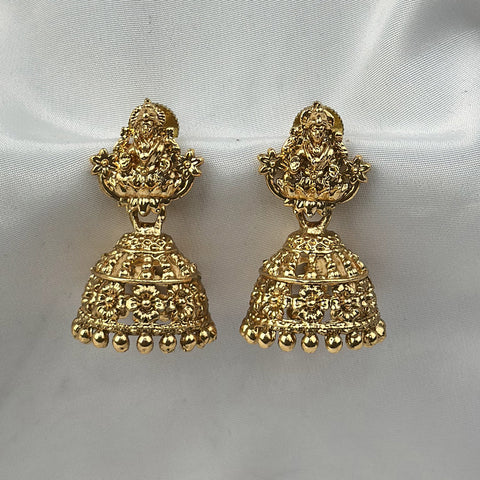 Gold earrings on a white satin background