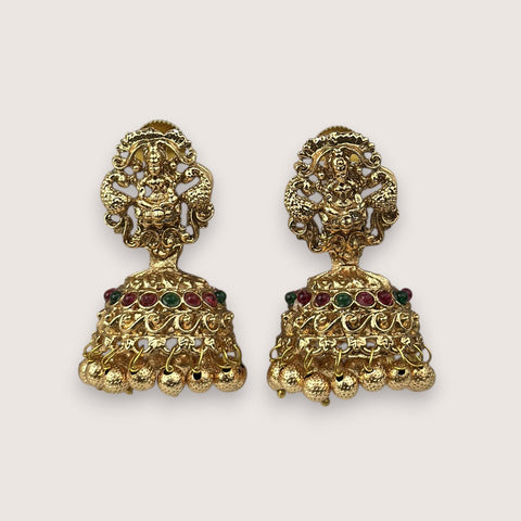 Pair of gold earrings with intricate designs and colored stones on a light beige background
