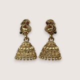 Gold earrings with intricate designs on a light beige background