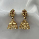 Pair of gold earrings with intricate designs on a white fabric background