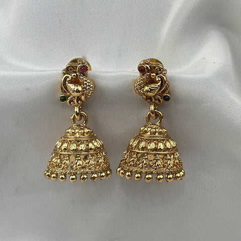Pair of gold earrings with intricate designs on a white fabric background