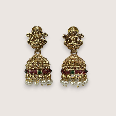 Pair of gold earrings with intricate designs and red stones on a white background