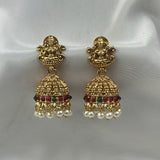 Gold earrings with pearls and gemstones on a white satin background