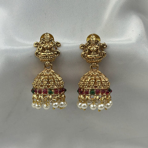 Gold earrings with pearls and gemstones on a white satin background