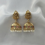 Gold earrings with pearl and gemstone accents on a white fabric background