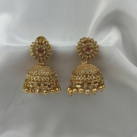 Gold earrings with intricate designs on a white fabric background