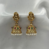 Gold earrings with pearls and gemstones on a white satin background