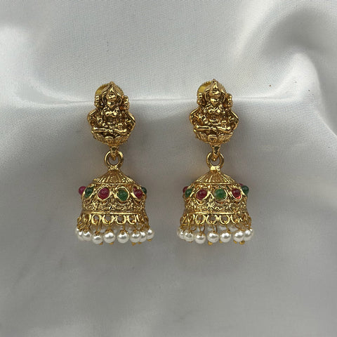 Gold earrings with pearls and gemstones on a white satin background