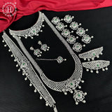Silver jewelry set with green gemstones on a black background