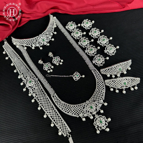 Silver jewelry set with green gemstones on a black background