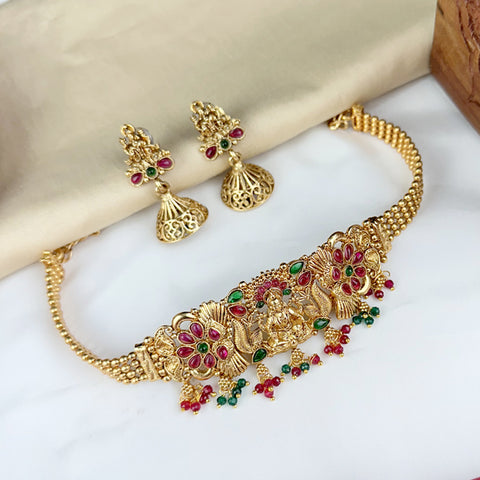 Gold necklace and earrings with gemstones on a white surface