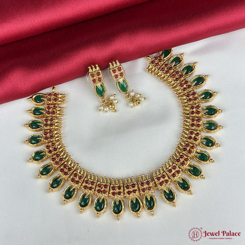Gold necklace with green and red stones on a white background