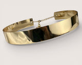 Gold choker necklace on a light gray background