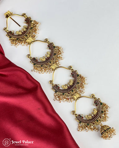 Gold earrings with intricate designs on a white background with red fabric.