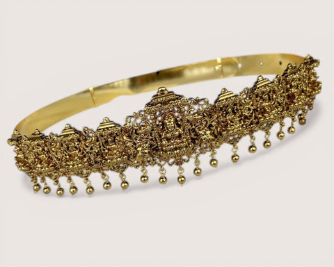 Gold headband with intricate designs and dangling beads on a white background