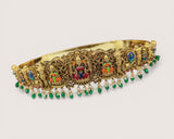 Decorative gold headband with colorful gemstones on a light beige background