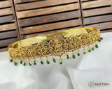 Gold necklace with green beads on a white fabric background