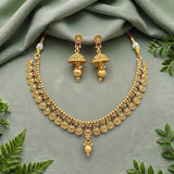 Gold-toned traditional Indian jewelry set featuring a necklace and matching earrings, styled on a sage green fabric background with decorative green leaves.