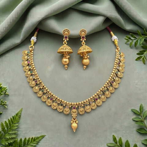 Gold-toned traditional Indian jewelry set featuring a necklace and matching earrings, styled on a sage green fabric background with decorative green leaves.