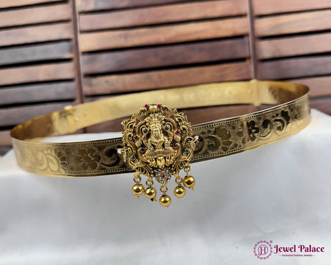 Gold bracelet with intricate design and pendant on a white surface with wooden background