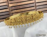 Gold necklace with intricate design on a white surface with wooden background