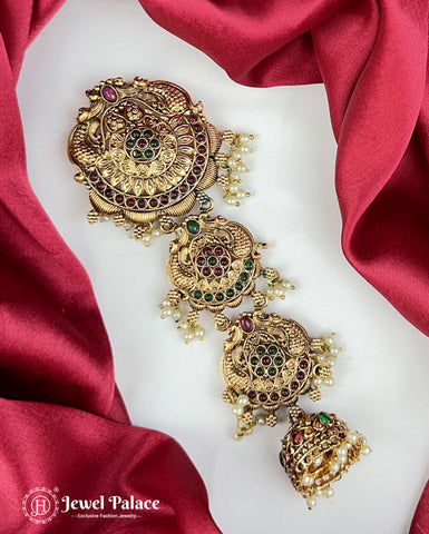 Gold jewelry set with green and red stones on a white surface with red fabric