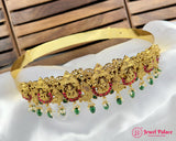 Gold necklace with red and green accents on a white fabric background