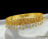 Gold bracelet with intricate designs and dangling beads on a white surface, branded 'Jewel Palace'.