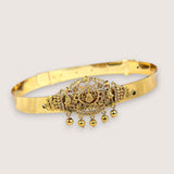Gold bracelet with intricate design and hanging beads on a light gray background