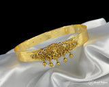 Gold tiara with intricate designs and dangling beads on a white satin background